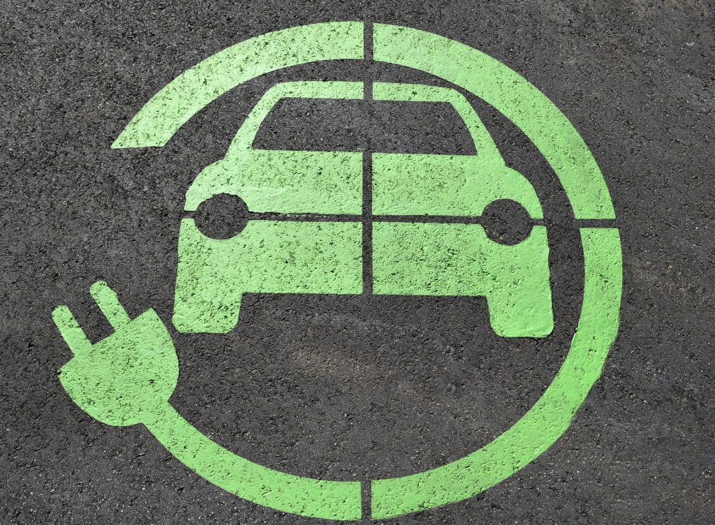 a green sign of a car and a socket on the asphalt