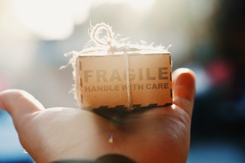 a hand holding a small woodel box with a phrase "fragile handle with care"