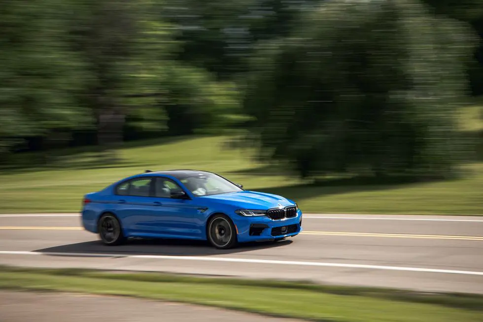 blue bmw m5 driving on highway