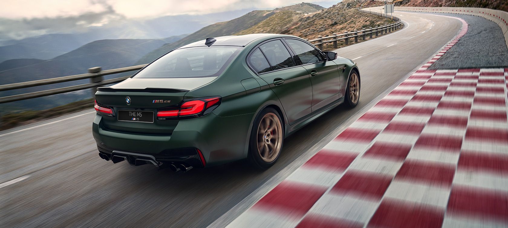 green BMW M5 CS rear angular view in the motion on the track
