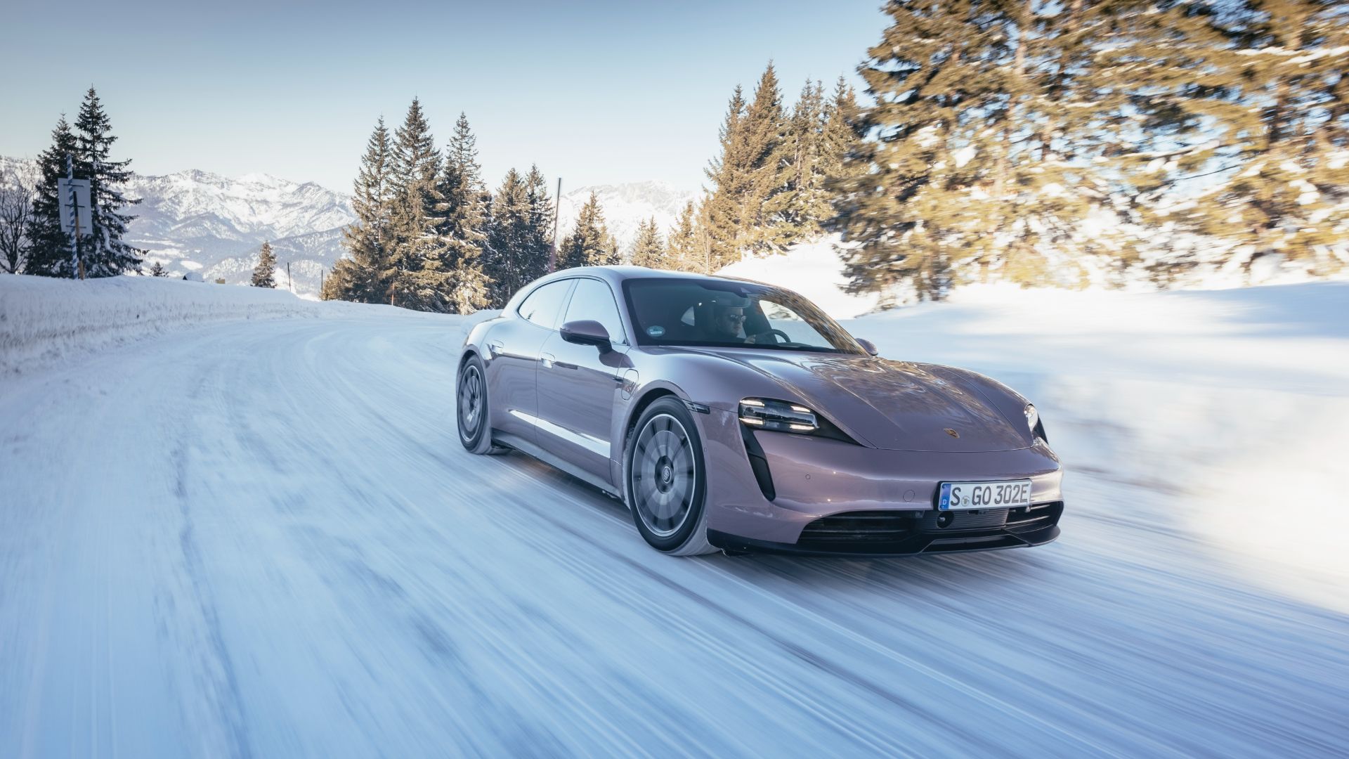 Porsche Taycan Sport Turismo front view in the motion in the snowy mountains