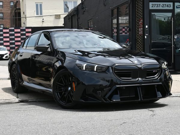 Front three-quarter view of the 2025 BMW M5 Hybrid, showcasing its aggressive stance and Iconic Glow grille.